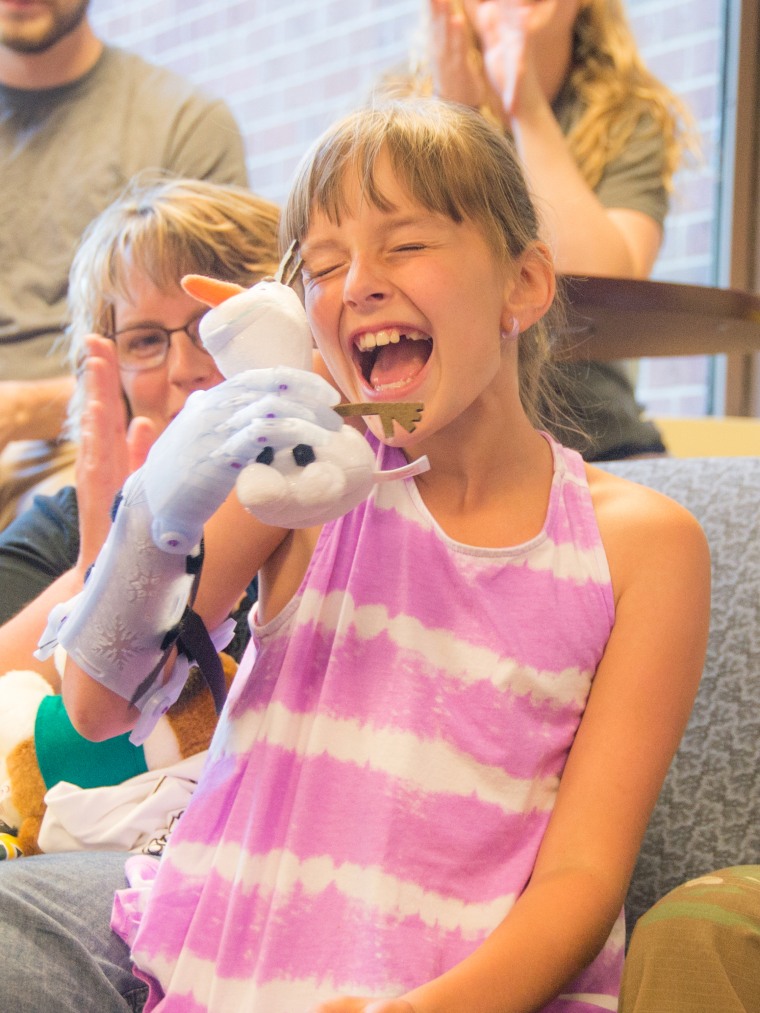 Karissa Mitchell, 9, is overjoyed at receiving a new prosthetic arm designed by Siena College physics students.