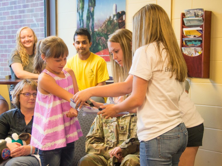 Siena senior Miranda Marnes puts a "Frozen"-themed prosthetic arm on 9-year-old Karissa Mitchell. She is helped by the other e-NABLE team leader Alyx Gleason.