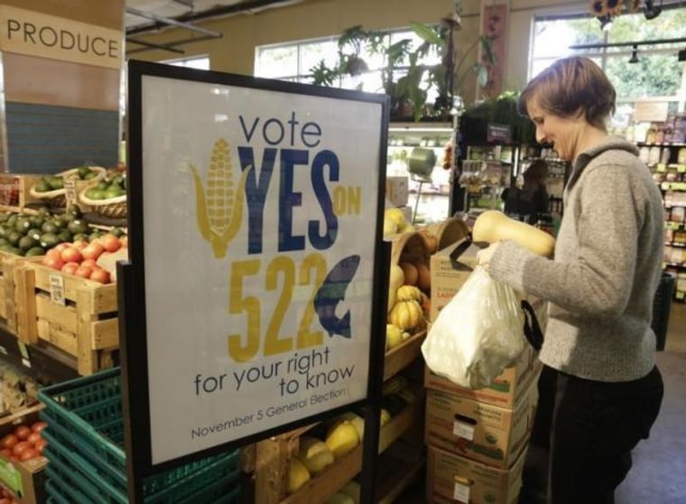 A customer picks up produce near a sign supporting a ballot initiative in Washington state that would require labelling of foods containing genetically modified crops at the Central Co-op in Seattle, Washington