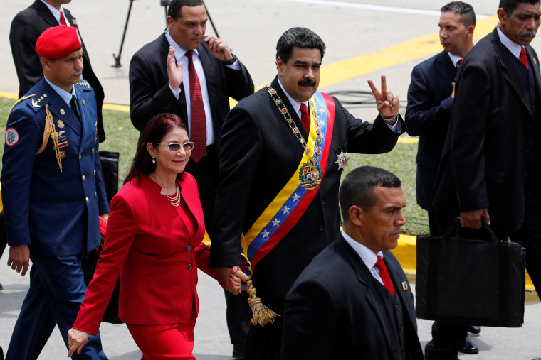 Venezuela's President Nicolas Maduro flashes the victory sign to the media next to her wife Cilia Flores in Caracas, Venezuela July 5, 2016.