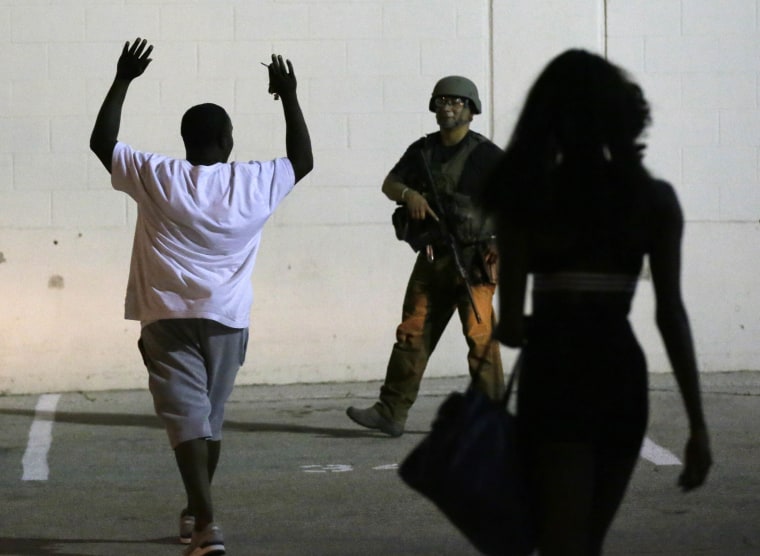 Image: A man raises his hands as he walks near a law enforcement officer