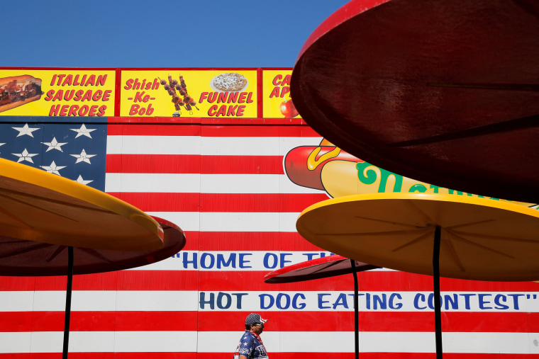 Image: A man dressed in American colors walks through a dining area before Nathan's Famous Fourth of July International Hot Dog-Eating Contest at Coney Island in Brooklyn, New York