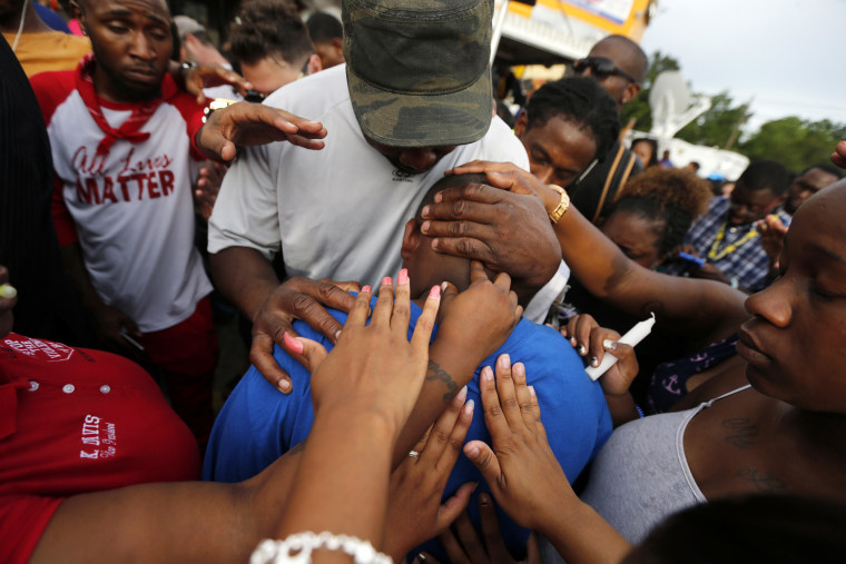 Image: Cameron Sterling, son of Alton Sterling, is comforted by hands from the crowd at a vigil
