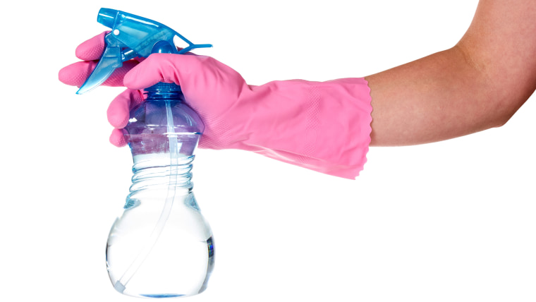 Hand in pink rubber glove holding clear spray bottle