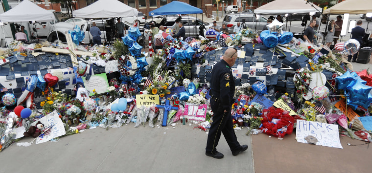 Image: A policeman visits a makeshift memorial at the Dallas police headquarters