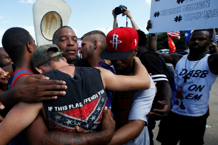 Image: People, including a man wearing a confederate flag, hug after taking part in a prayer circle after a Black Lives Matter protest following the multiple police shootings in Dallas