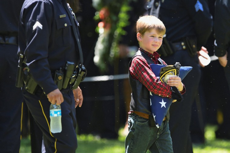 Image: Magnus Ahrens carries a folded U.S. flag after the burial ceremony for his father, Dallas Police Department Senior Corporal Lorne B. Ahrens, who was among five police officers shot dead the previous week, at Restland Public Safety Memorial Gardens