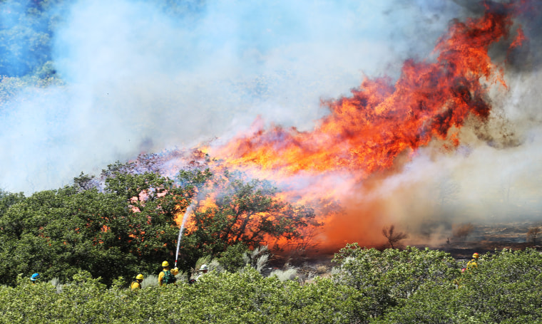 Fire crews work to put out a brush fire Tuesday, Sept. 1, 2015, in Cottonwood Heights, Utah.