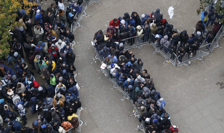 Image: Migrants queue outside Office of Health and Social Affairs as they wait to register in Berlin