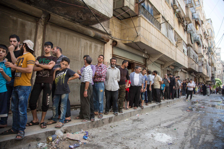 Image: Syrians queue up to buy bread in Aleppo