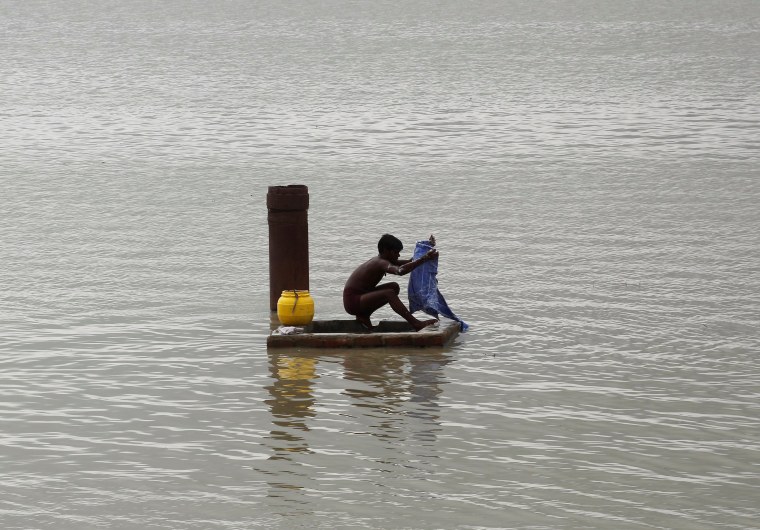 Image: A man washes clothes on the flooded banks of river Ganga after heavy rains in Allahabad