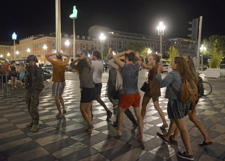 Image: People cross the street with their hands on thier heads as a French soldier secures the area after at least 60 people were killed in Nice when a truck ran into a crowd celebrating the Bastille Day national holiday