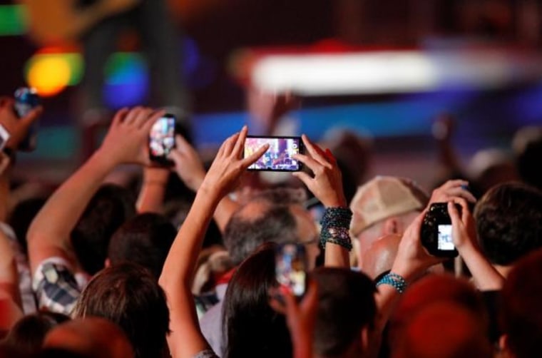 A fan uses a cell phone to record a performance during the 2014 CMT Music Awards in Nashville
