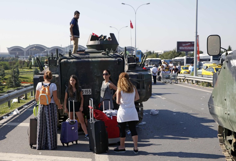 Image: Women stand behind a military vehicle in front of Sabiha Airport, in Istanbul