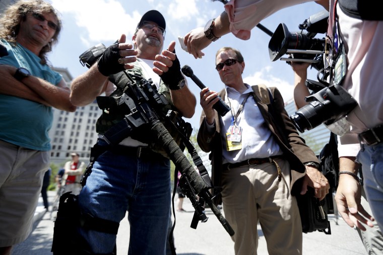 Image: Second Amendment supporter Steve Thacker carries an AR-15-style weapon as he talks to the media during a protest