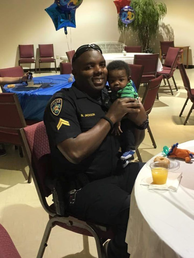 Image: Baton Rouge Police Officer Montrell Jackson, holds his son Mason at a Father's Day event for police officers in Baton Rouge