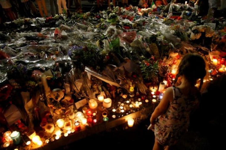 A child stands near flowers and candles placed to pay tribute to victims of the truck attack along the Promenade des Anglais on Bastille Day that killed scores and injured as many in Nice