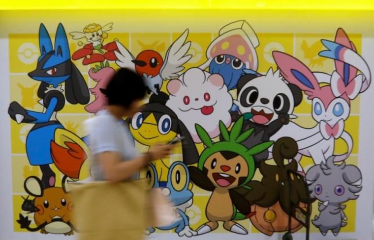 A woman using a mobile phone walks past a shop selling Pokemon goods in Tokyo