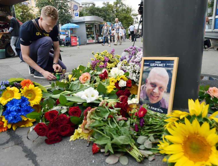 Image: A man lights a candle where journalist Pavel Sheremet was killed