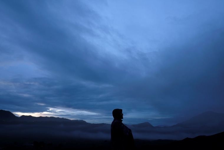 Image: A Hindu villager stand along the edge of the Mount Bromo volcanic crater during the Kasada ceremony in Probolinggo