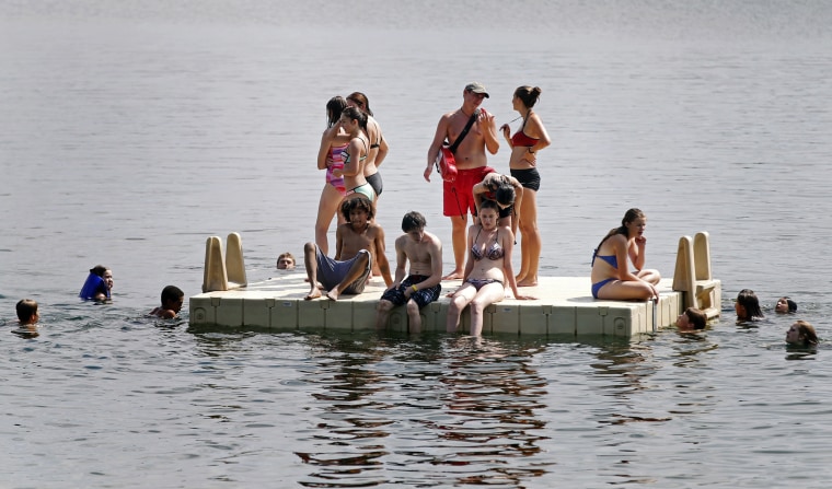 A lifeguard, center in red, overseas a platform as people beat the oppressive heat and humidity on July 21, at Lake Harriet in Minneapolis. Heat warnings were in effect as temperatures reached to the mid-90's with the heat index topping 100-degrees with tropical-like dew points.