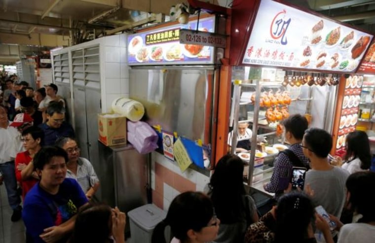 People queue outside hawker Chan Hong Meng's Michelin star awarded stall, for his soya sauce chicken rice and noodle at a food market in Singapore