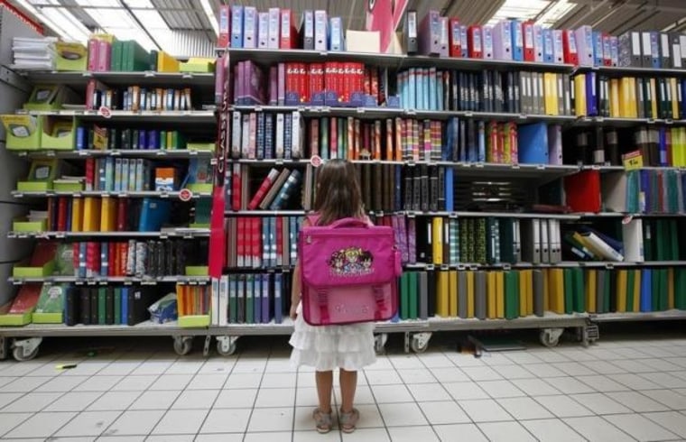 A young girl looks at school at school stationery in a supermarket in Nice
