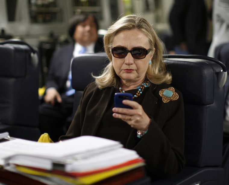 Then Secretary of State Hillary Clinton checks her Blackberry from a desk inside a C-17 military plane upon her departure from Malta, in the Mediterranean Sea, bound for Tripoli, Libya on Oct. 18, 2011.