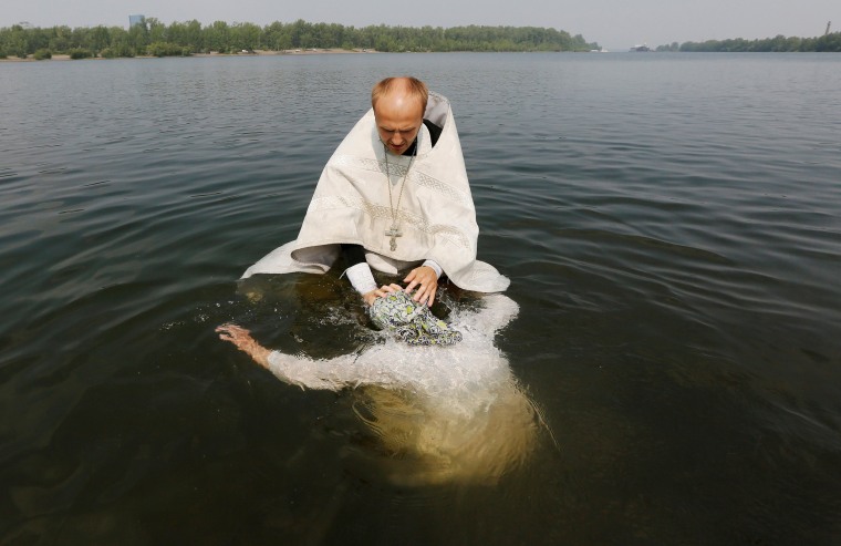 Image: An orthodox priest baptises a woman in Yenisei river during a ceremony marking the Christianisation of the country which was known as Kievan Rus' in Krasnoyarsk