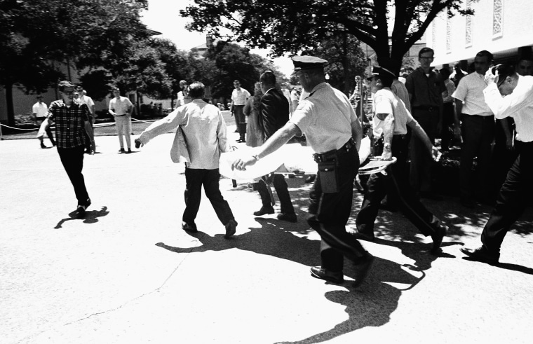 FILE: In this Aug. 1, 1966 file photo, one of the victims of Charles Joseph Whitman, the sniper who gunned down victims from a perch in the University of Texas tower, is carried across the campus to a waiting ambulance in Austin.
