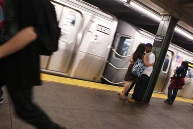 A couple embraces as a subway train arrives in the station in New York
