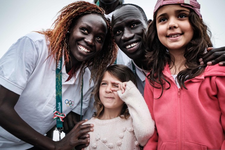 Image: Anjelina Nada Lohalith and James Nyang Chiengjiek with tourists