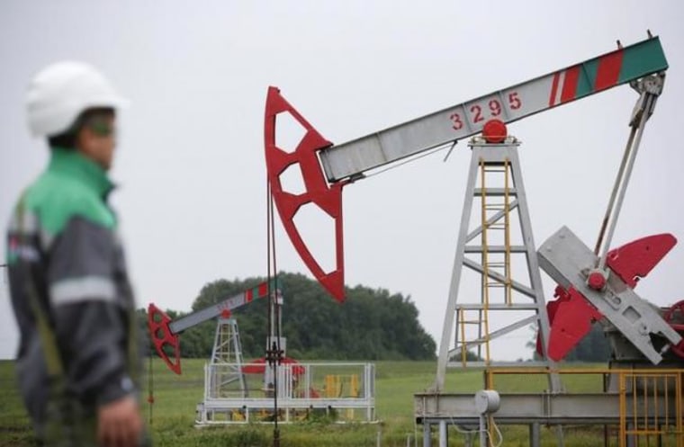 Worker looks at pump jack at oil field Buzovyazovskoye owned by Bashneft company north from Ufa