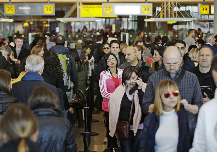 Travelers wait in a winding line to pass through customs and border control at John F. Kennedy Airport in New York in 2013.
