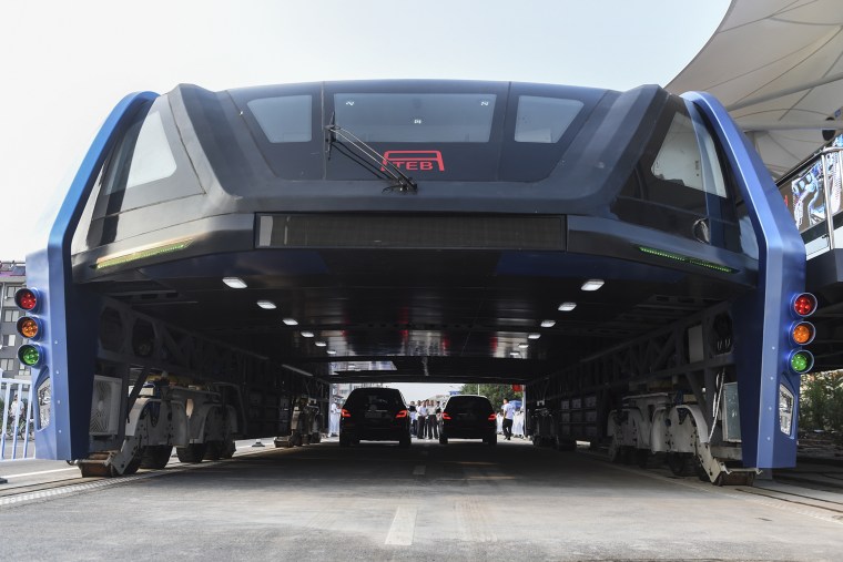 People look at the Transit Elevated Bus TEB-1 run past vehicles as they conducted a test run in Qinhuangdao, north China's Hebei Province.