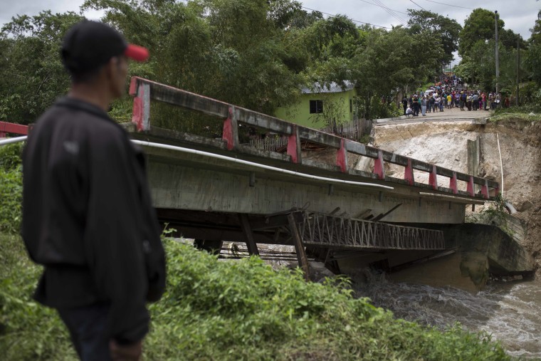 Residents stand before a collapsed bridge brought down by Hurricane Earl in the Arroyito neighborhood, in Melchor de Mencos, Guatemala, on the Peten border with Belize, Thursday, Aug. 4, 2016.