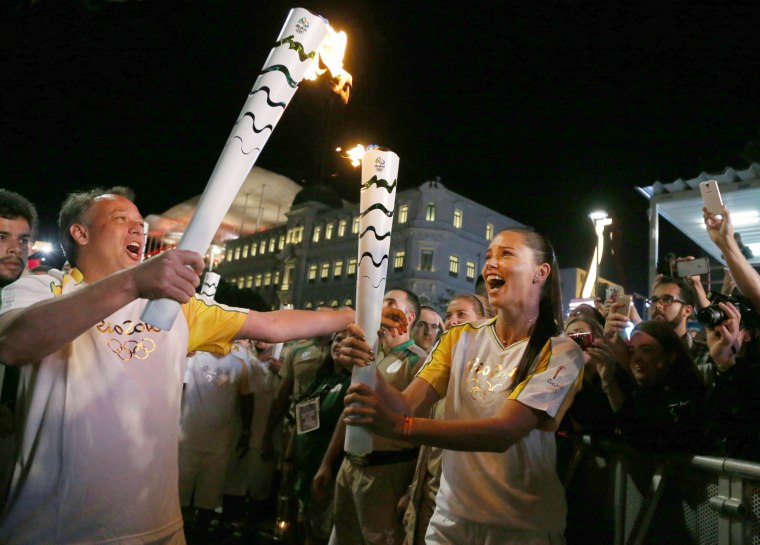 Image: Model Adriana Lima carries the Olympic torch with Rio de Janeiro's Secretary of Tourism Antonio Pedro in Maua Square in Rio de Janeiro