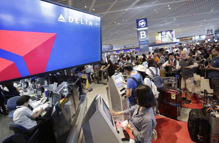 Image: Passengers check in at the Delta counter at Narita airport in Tokyo on Tuesday