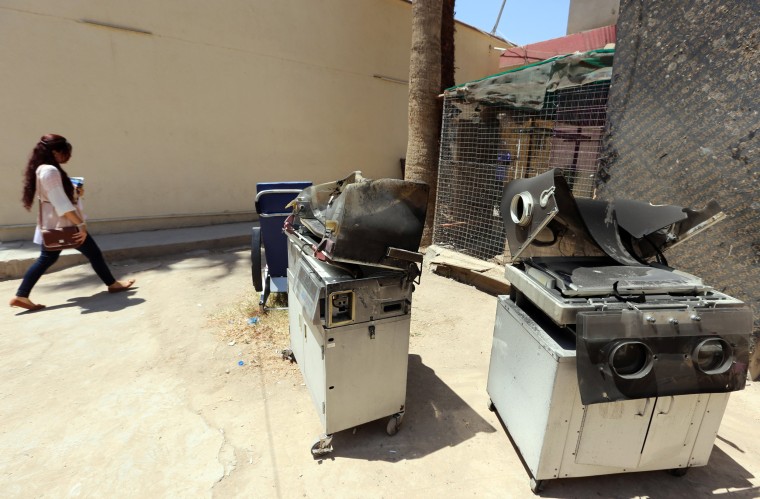 Image: An Iraqi woman walks past burnt incubators