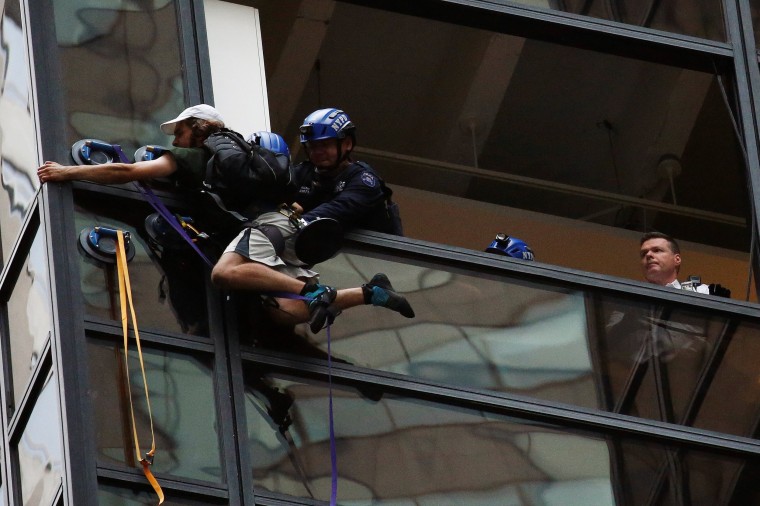 Image: Officers from the NYPD embrace a man to stop him from climbing the outside of Trump Tower in New York