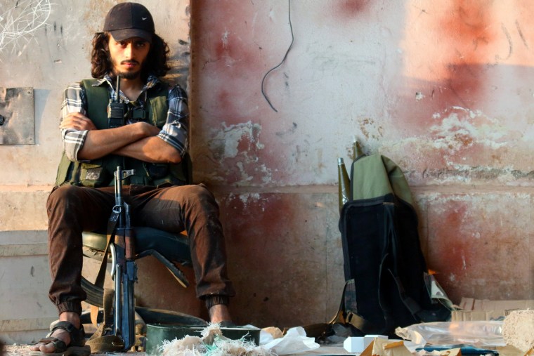 Image: A rebel fighter sits with his weapon in the artillery academy of Aleppo