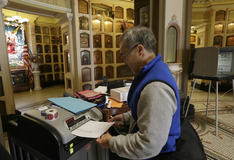 Image: Jeff Young enters a ballot into a voting machine in San Francisco