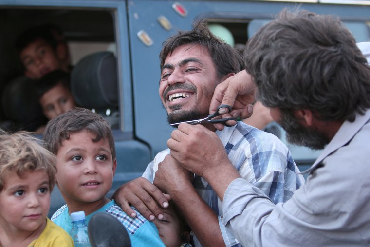 Image: A man cuts the beard of a civilian who was evacuated with others by the Syria Democratic Forces (SDF) fighters from an Islamic State-controlled neighbourhood of Manbij
