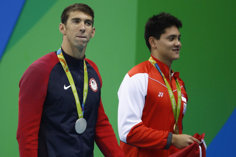 Image: Silver medalist Michael Phelps waves next to gold medalist Joseph Schooling from Singapore after the Men's 100m Butterfly Final.