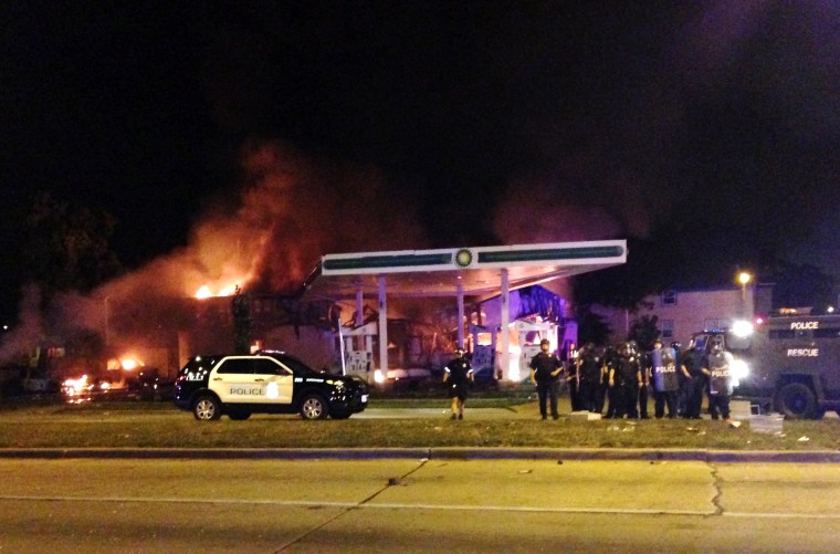 Authorities respond near a burning gas station as dozens of people protest following the fatal shooting of a man in Milwaukee, Saturday, Aug. 13, 2016.