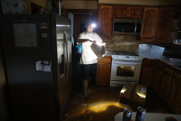 Image: Tommy Gallagher retrieves items from his flooded home on Aug. 17, in Sorrento, Louisiana. Last week Louisiana was overwhelmed with flood water causing at least twelve deaths and thousands of homes damaged by the flood waters.