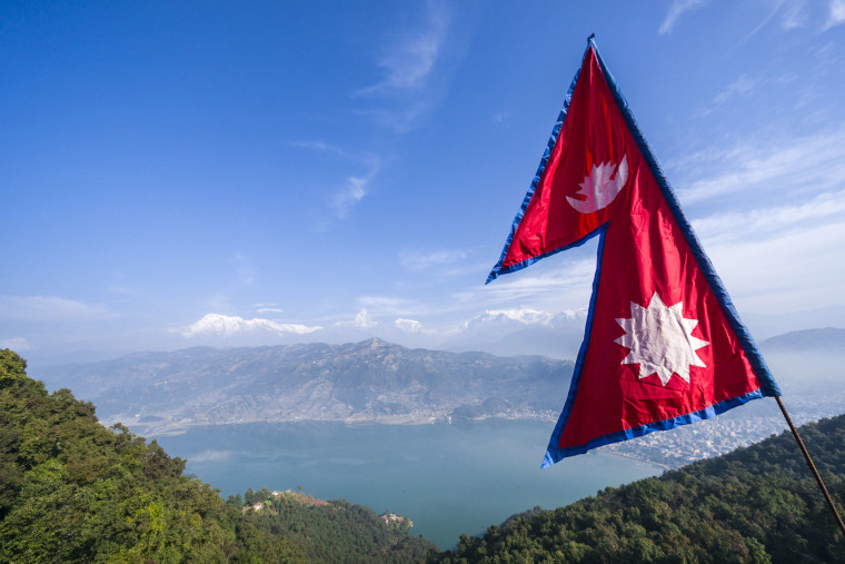 The nepali national flag is weaving high above the Phewa