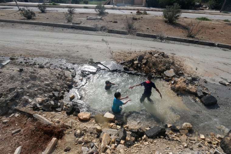 Image: Boys cool down with water from a damaged water pipe in Aleppo, Syria, on Aug. 20, 2016