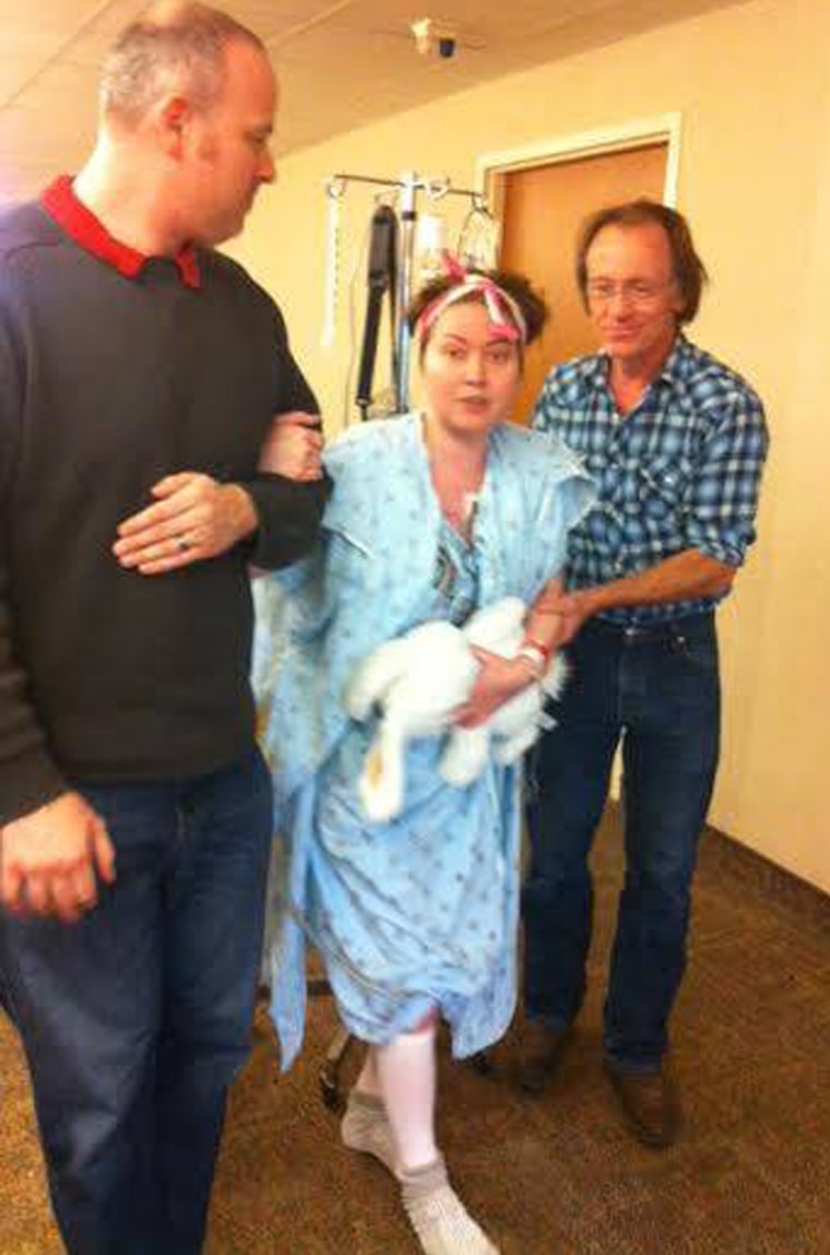 Amber???s husband and father help her walk after surgery in 2014.