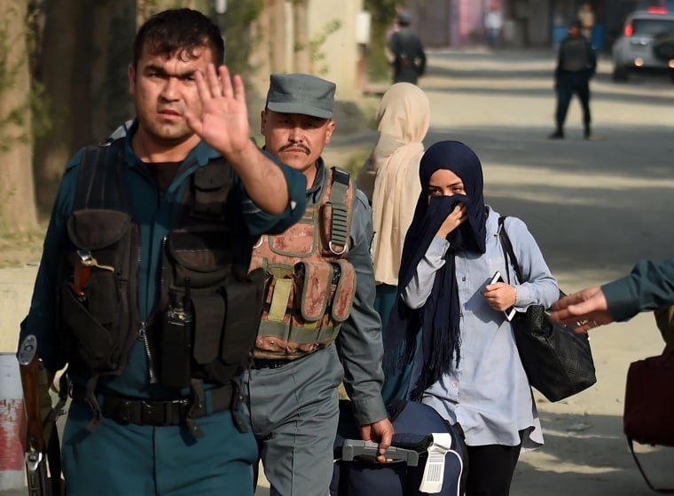 Image: A student who had been trapped inside the American University of Afghanistan during the attack is escorted out by police